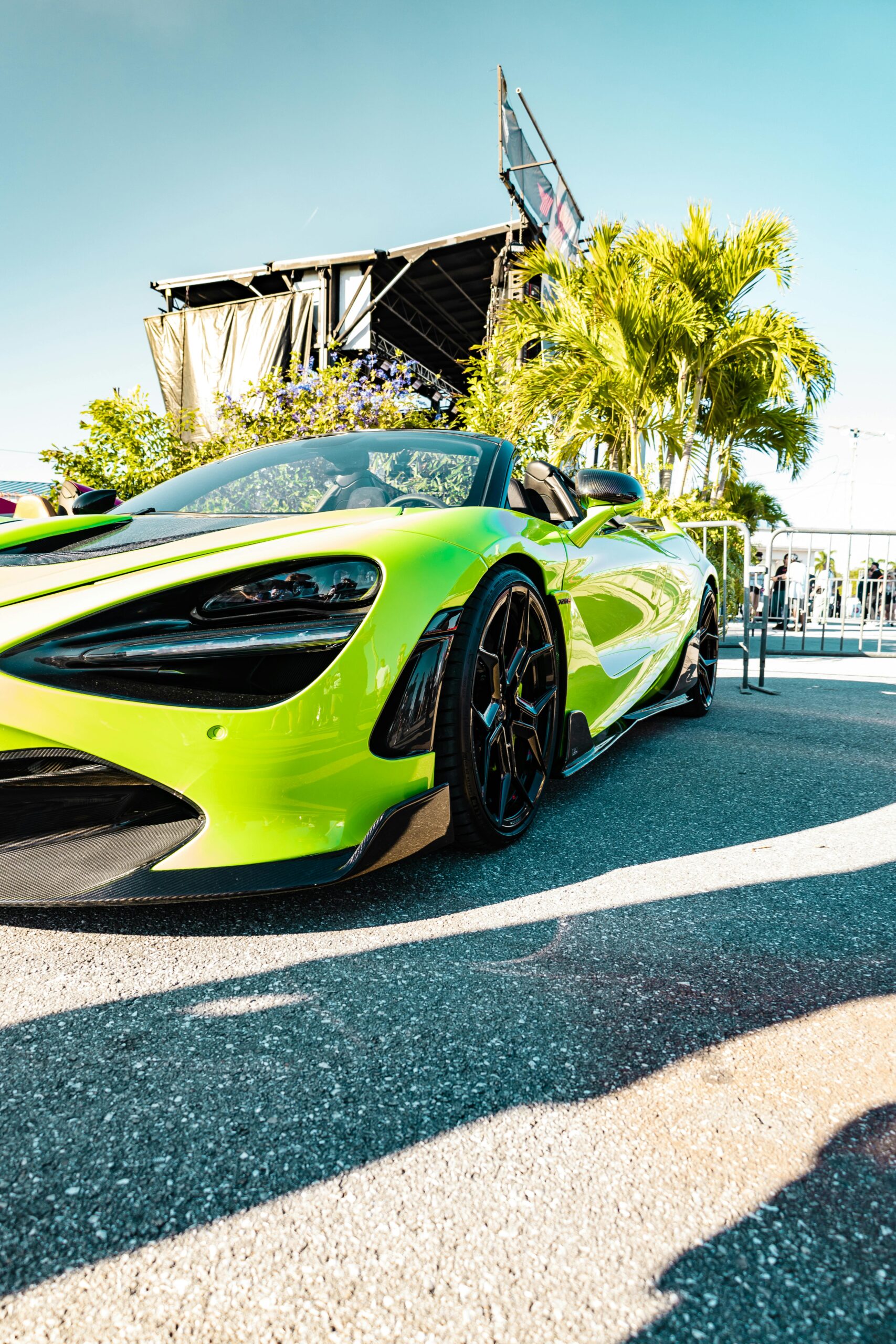 Eye-catching green supercar showcased at a sunlit outdoor event, reflecting luxury and speed.