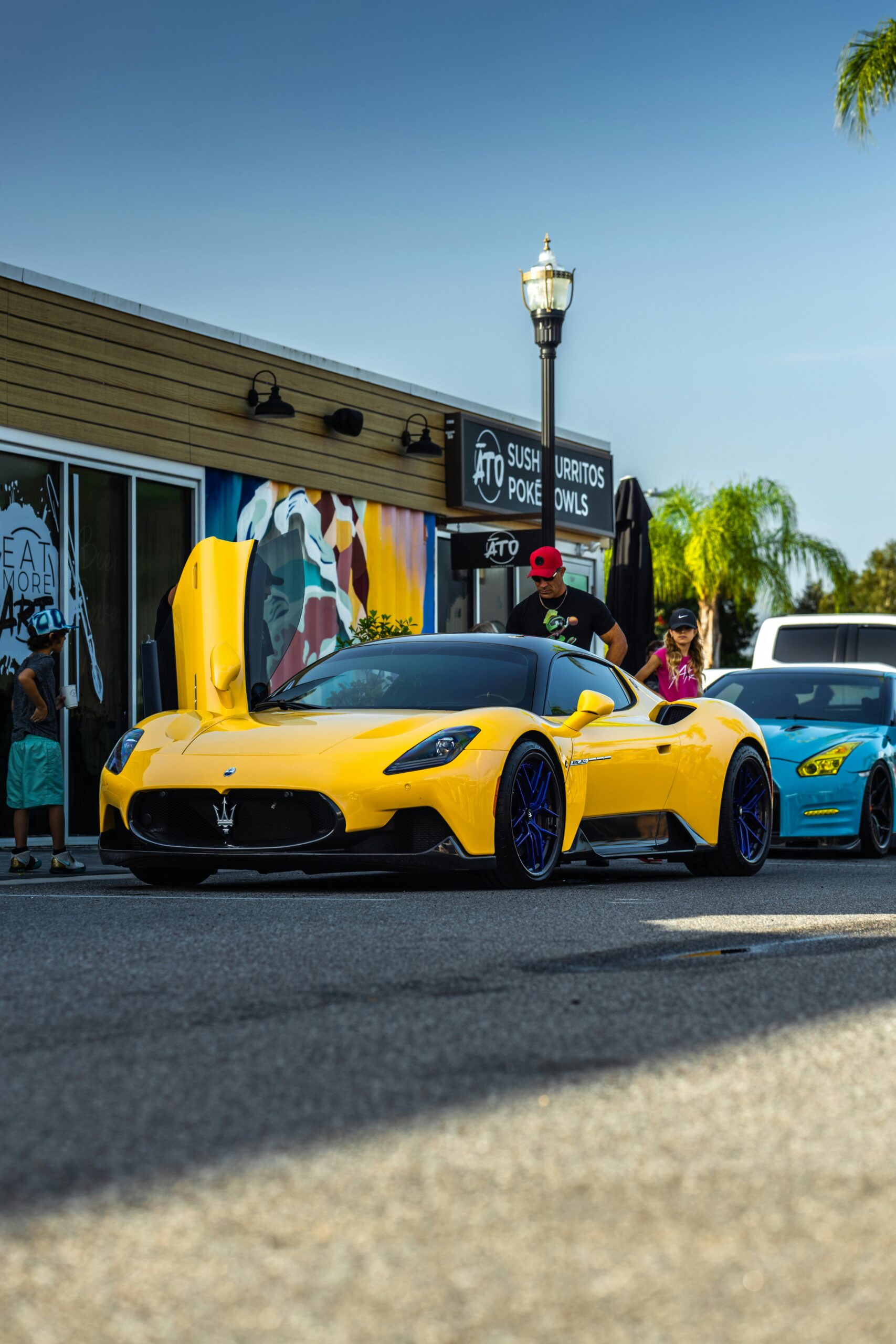 Bright yellow Maserati MC20 showcased outdoors with vibrant blue wheels in Wesley Chapel, Florida.